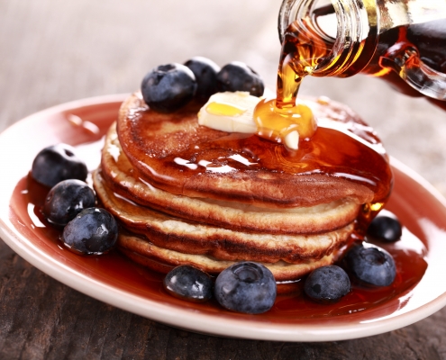 Photo of a plate of pancakes with syrup and blueberries