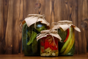 Canned vegetables in glass jars on a wooden background. Pickles. Pickled cucumbers and peppers.