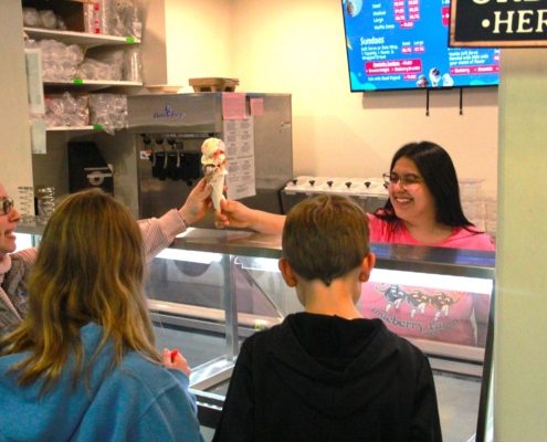 Degrandchamps employee handing a family ice cream at the ice cream counter