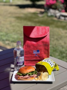 Sandwich, chips, and a water on a picnic table