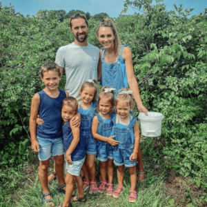 Family in front of a blueberry bush