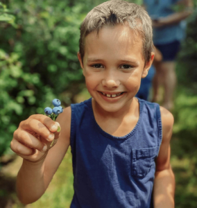 Boy holding up blueberries to the camera